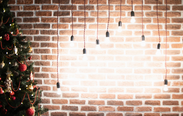 挂着灯的砖墙上挂着圣诞树。明亮的圣诞背景图片下载