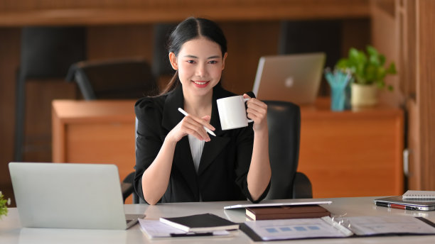 女老板边喝咖啡边用笔记本电脑工作图片下载