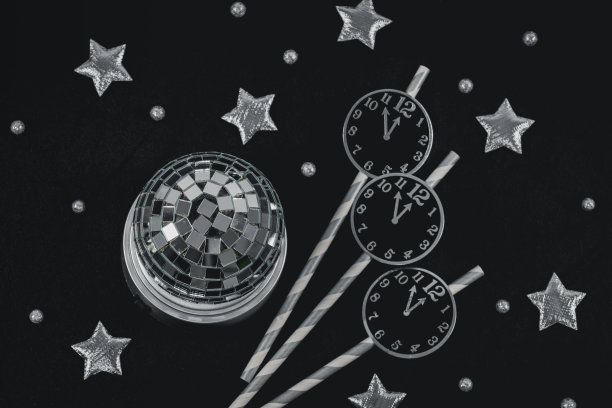 稻草上的纸钟，银色的星星，黑色背景上的迪斯科球和雪球图片下载