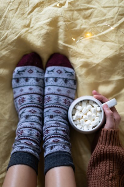 一个女孩手里拿着一大杯可可，坐在温暖的袜子上。图片下载