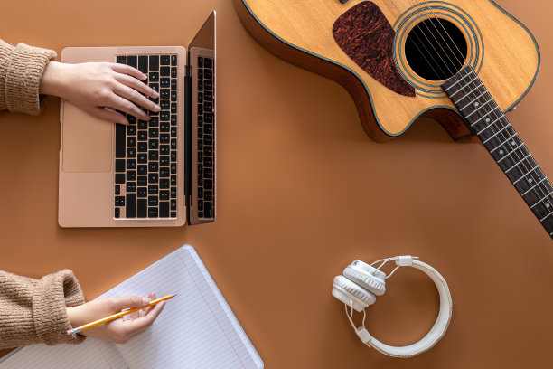 音乐背景与原声吉他，笔记本电脑和女性的手，俯视图。图片下载