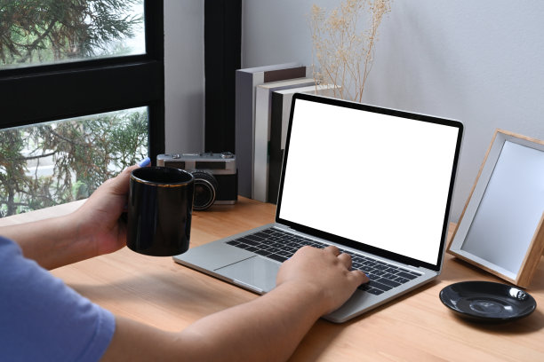 拍摄年轻女性拿着咖啡杯，用笔记本电脑工作。图片下载