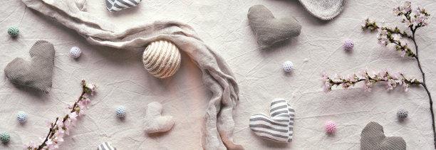 手工纺织的心和球在棉花背景。中性色的纺织工艺品。冬天的樱花树枝和蜡烛。单色看图片下载