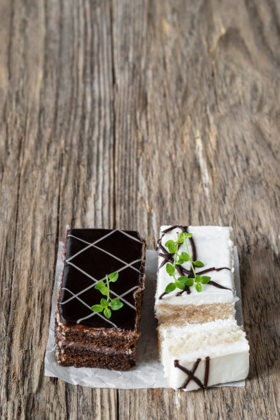 木桌上放着白巧克力和黑巧克力蛋糕片和奶油图片下载