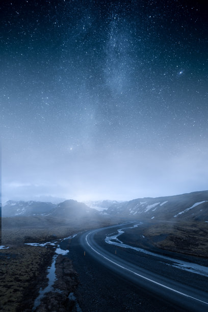 冰岛蜿蜒潮湿的道路通向布满星星和银河的群山。图片下载