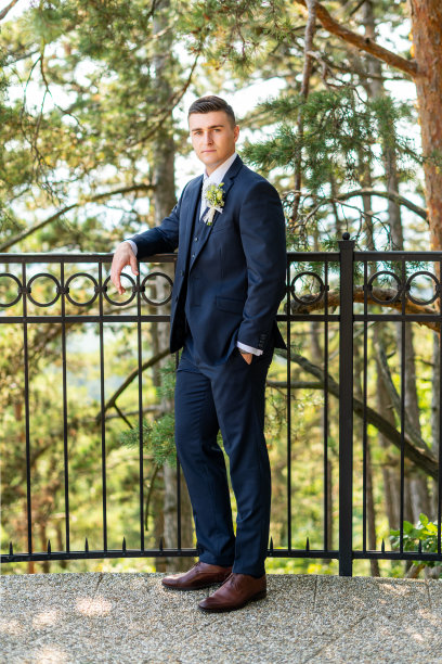 英俊年轻的新郎穿着优雅的深蓝色西装看着摄像机的户外肖像。时尚新郎时尚。图片下载