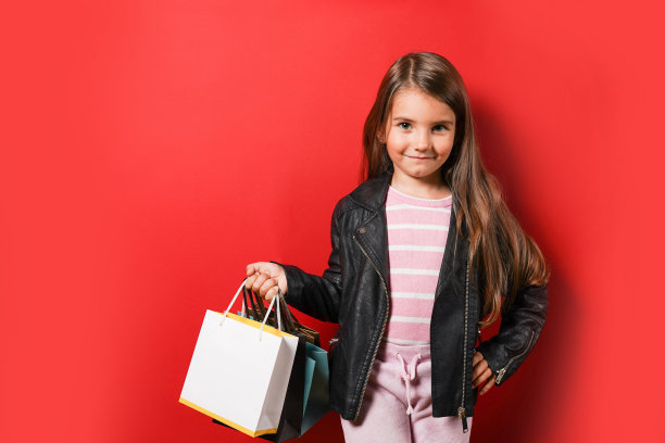 漂亮的小女孩，红色背景上有购物纸袋图片下载