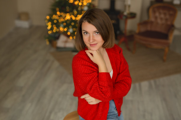 一个女人拿着一棵背景有灯光的圣诞树。图片下载