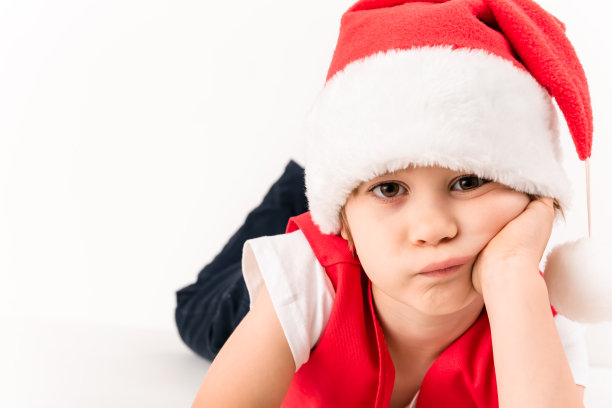 特写人物躺着的愤怒的小孩子在红色圣诞老人的帽子孤立在白色的背景。漂亮的五岁欧洲男孩。等待一个礼物。副本的空间。圣诞快乐。没有心情。新的一年图片下载