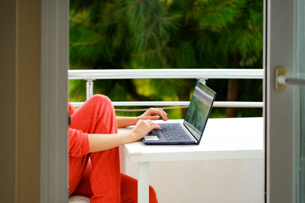 一个女人在阳台上用笔记本电脑工作图片下载
