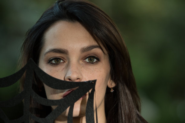 一位黑发碧眼美女的肖像。照片在深绿色模糊的背景。图片下载