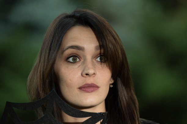 一位黑发碧眼美女的肖像。照片在深绿色模糊的背景。图片下载