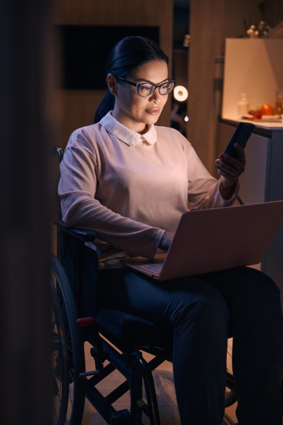 一位患有偏瘫的微笑女性在家里使用电子设备图片下载