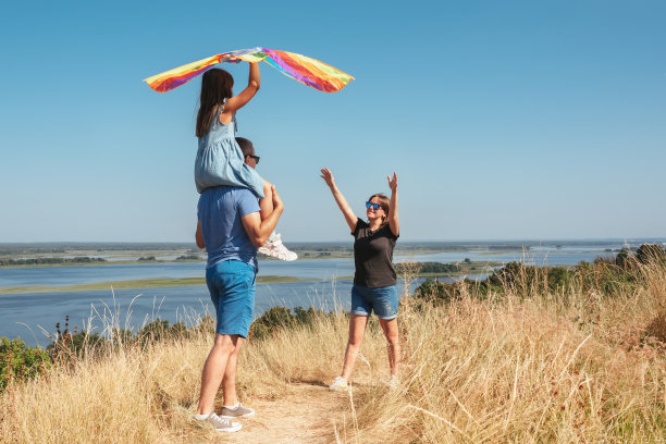 一个阳光明媚的日子，幸福的一家人带着风筝在大自然中玩耍图片下载