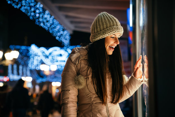 一位年轻女子看着商店橱窗的画像。购物人销售概念图片下载