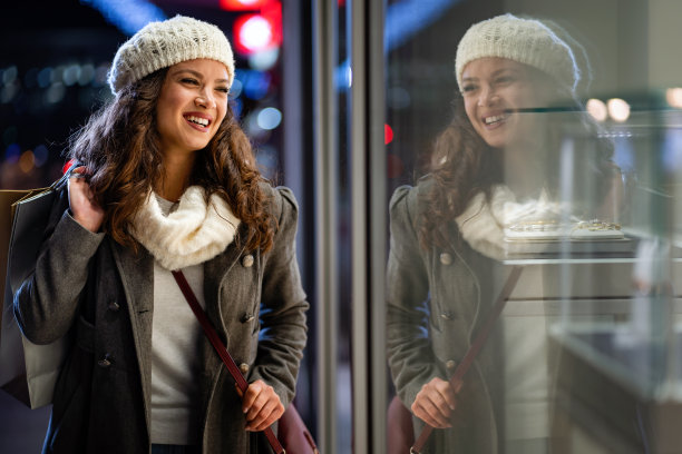 年轻快乐的女人带着购物袋走在街上，买圣诞礼物。图片下载