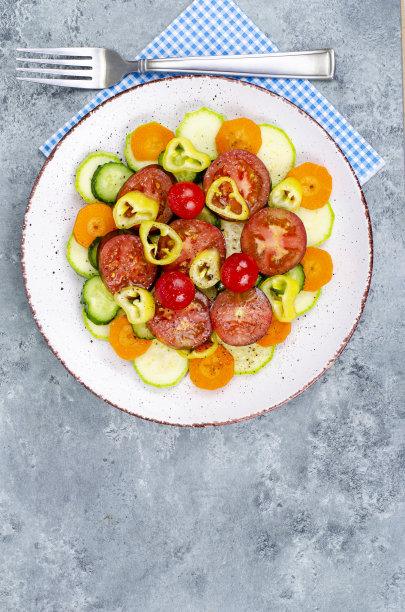 将应季蔬菜切片，放在灰蓝色背景的盘子里。工作室的照片。图片下载