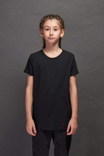 小女孩穿着黑色t恤与空间为您的标志或设计在工作室的灰色背景图片下载