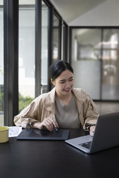 微笑的年轻女设计师在创意办公室工作。图片下载