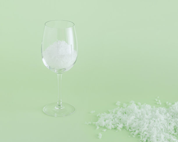 2022年，简约抽象的冬季节日场景，葡萄酒杯和雪被隔离在柔和的绿色背景上。新年或圣诞节的邀请卡的概念，或夏天的茶点的想法。图片下载