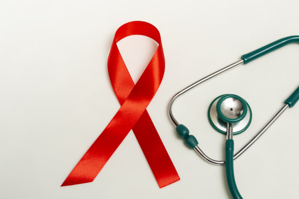 12月世界艾滋病日的医学概念。红色丝带和白色背景上的绿色医用听诊器。关闭复制空间图片下载