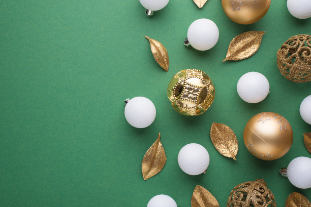 顶视图照片的金色和白色的圣诞树球和金色的叶子在孤立的绿色背景与copyspace图片下载