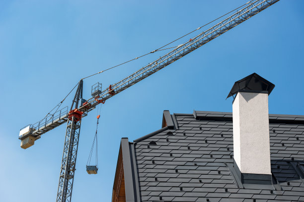 建筑工地-晴朗蓝天上的起重机和屋顶图片下载