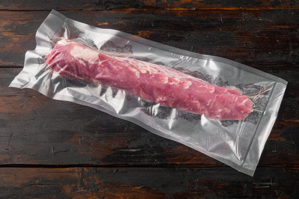 真空包装的生有机猪里脊肉，在旧的深色木桌背景，有文字空间和文字空间图片下载
