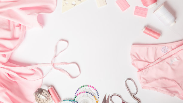 缝纫业务。裁缝的工作场所，有线，剪刀，模板，线轴，粉色织物。白色背景顶部视图空间的文本在框架。裁剪的概念图片下载