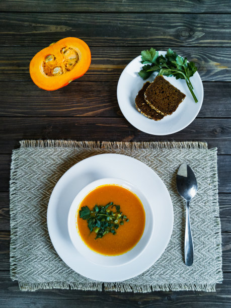南瓜汤与欧芹和大葱在深色木桌的俯视图图片下载