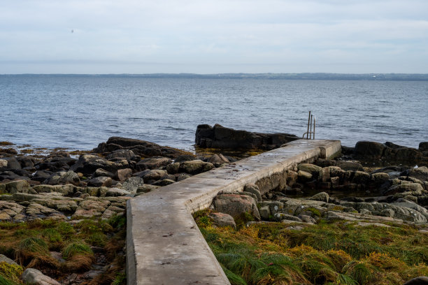 有混凝土防波堤的岩石海岸线。蓝色的海水和蓝色的天空作为背景。图片来自瑞典斯卡尔德维肯图片下载