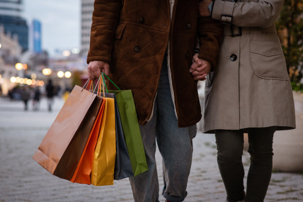 一对年轻夫妇在街上走着。那个年轻人手里提着购物袋。剪下。图片下载