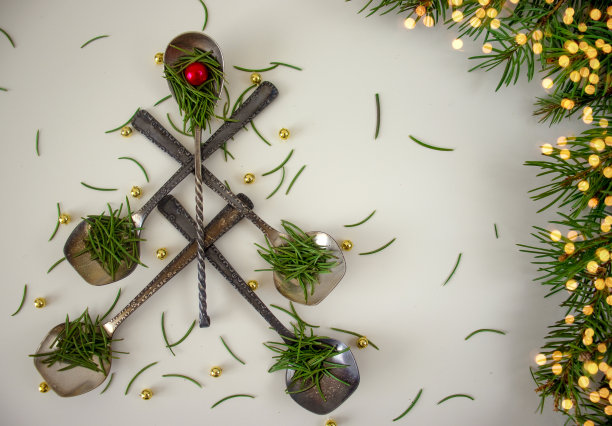 这是一棵用勺子做成的创意圣诞树，上面装饰着冷杉球果和冷杉针，背景是一串手工艺品的模糊斑点，俯视图，平躺着。圣诞节的食物菜单图片下载