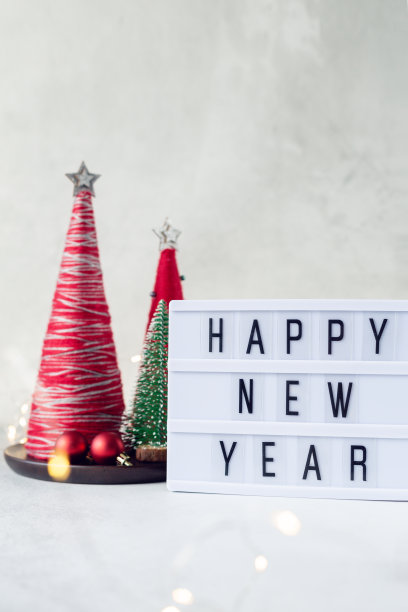灯箱与文字新年快乐与纱线包裹圣诞圆锥形树。新年的庆祝活动。软对焦，散景效果图片下载