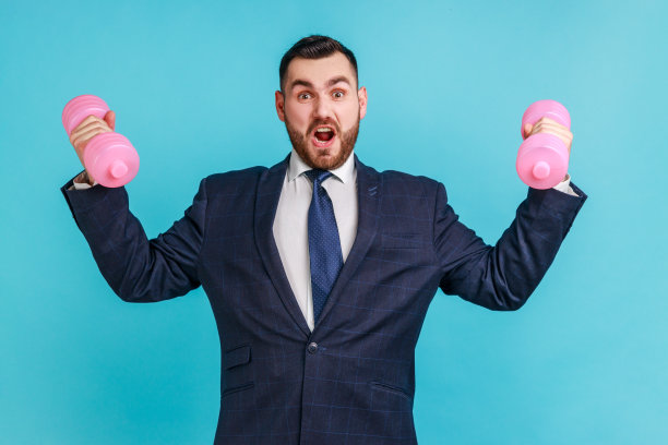 自信的商人穿着正装，用粉色哑铃训练二头肌和三头肌图片下载