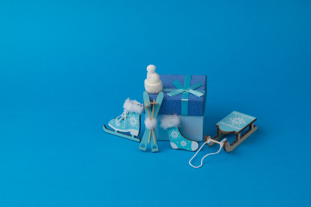帽子，溜冰鞋，袜子，雪橇和蓝色背景上的礼盒。图片下载