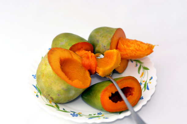 新鲜切片的芒果，盘中盛放，配有勺子，白色背景，选择性聚焦。芒果是热带树木芒果树的可食用核果图片下载