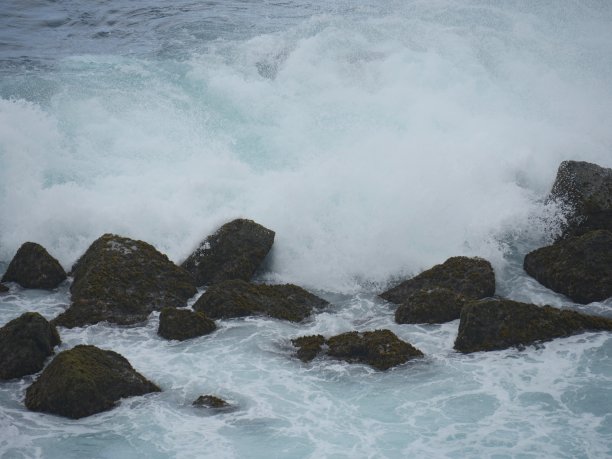 靠近海滩的白色浪花撞击岩石的特写图片下载