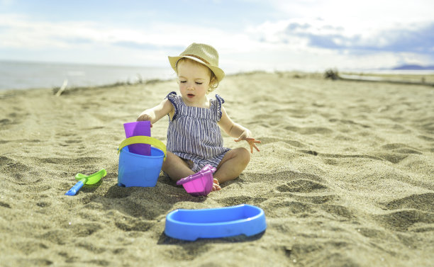 可爱的小女孩在沙滩上玩她的玩具图片下载
