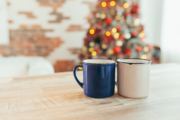 两个圣诞杯的特写照片，在新年的背景上，圣诞树和彩灯，在厨房的桌子上图片下载