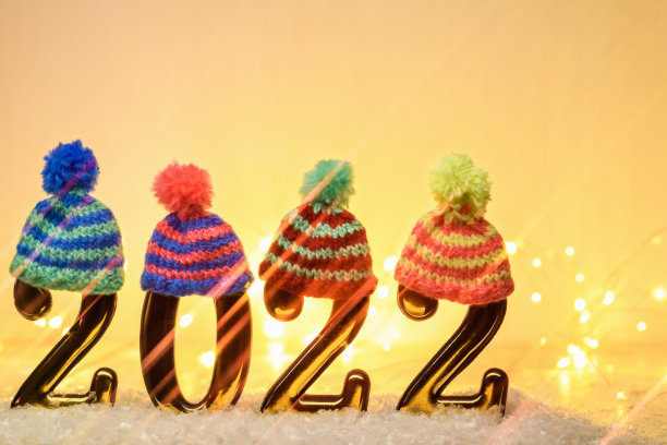 金色号码2022与多色针织帽变形滤镜和发光的花环在黄色背景。新的一年是2022年图片下载