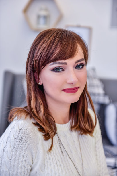 圣诞画像上一位年轻女子身穿白色针织长毛衣连衣裙，打着打底裤，坐在床上图片下载