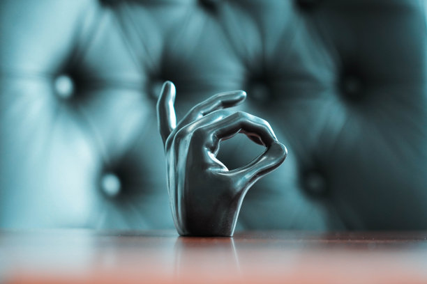 在办公室的一张棕色木桌上，一张黑色皮椅旁，放着一张黑色手掌的照片，上面写着“没问题”的字样图片下载