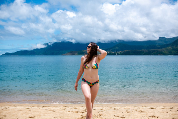 一位女士正在度假，在海滩上享受阳光灿烂的一天图片下载