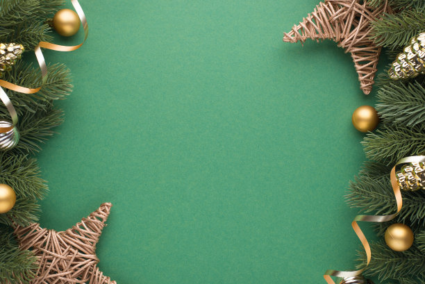 顶部视图照片的金色和银色的圣诞树球，蛇形和柳条藤的松树树枝上的星星在孤立的绿色背景与空的空间图片下载