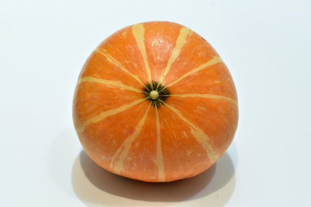 白色的桌子上放着一个成熟的条纹橙色南瓜。图片下载