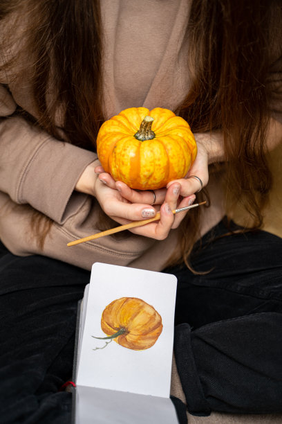 黑发女人坐着拿着小南瓜靠近水彩南瓜画图片下载