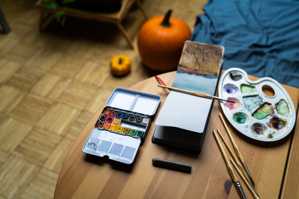 水彩画，刷子和调色板在桌子旁边的纸笔记本与图纸图片下载