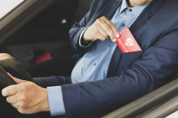 有身份证的男人。穿蓝色西装的人出示红色的身份证或通行证。一个重要的贱民正在开车。俄罗斯内政部在红色文件上的题词。图片下载