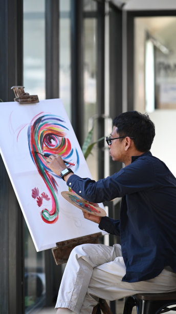 年轻的亚洲男性艺术家在明亮的工作室画布上作画。图片下载